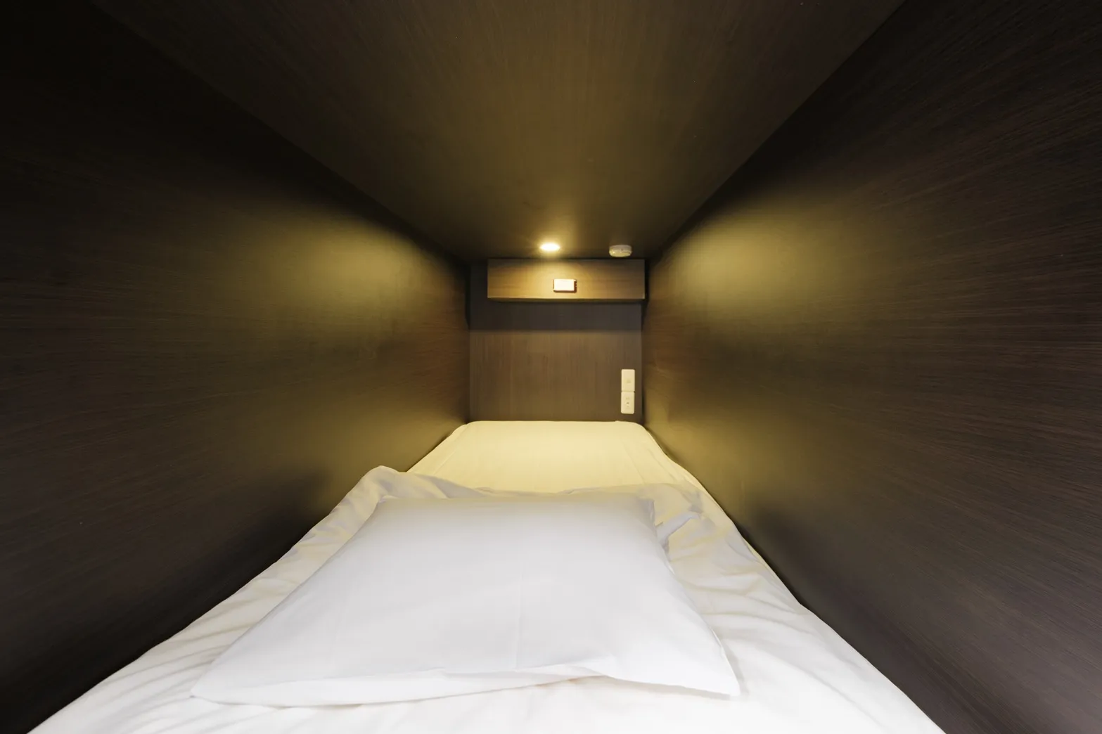 Dormitory capsule bed interior with USB outlet and reading light at Hostel JAZ Ueno
